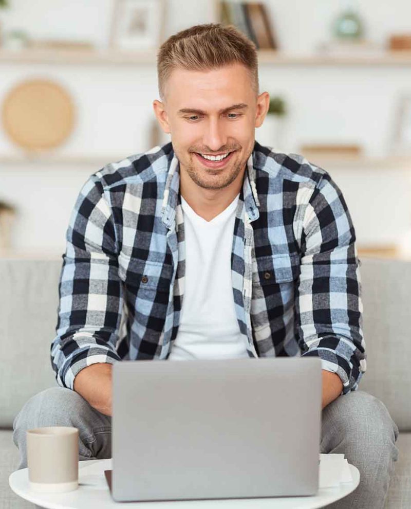 happy-man-chatting-online-on-laptop-with-friend-at-CHURUJ7